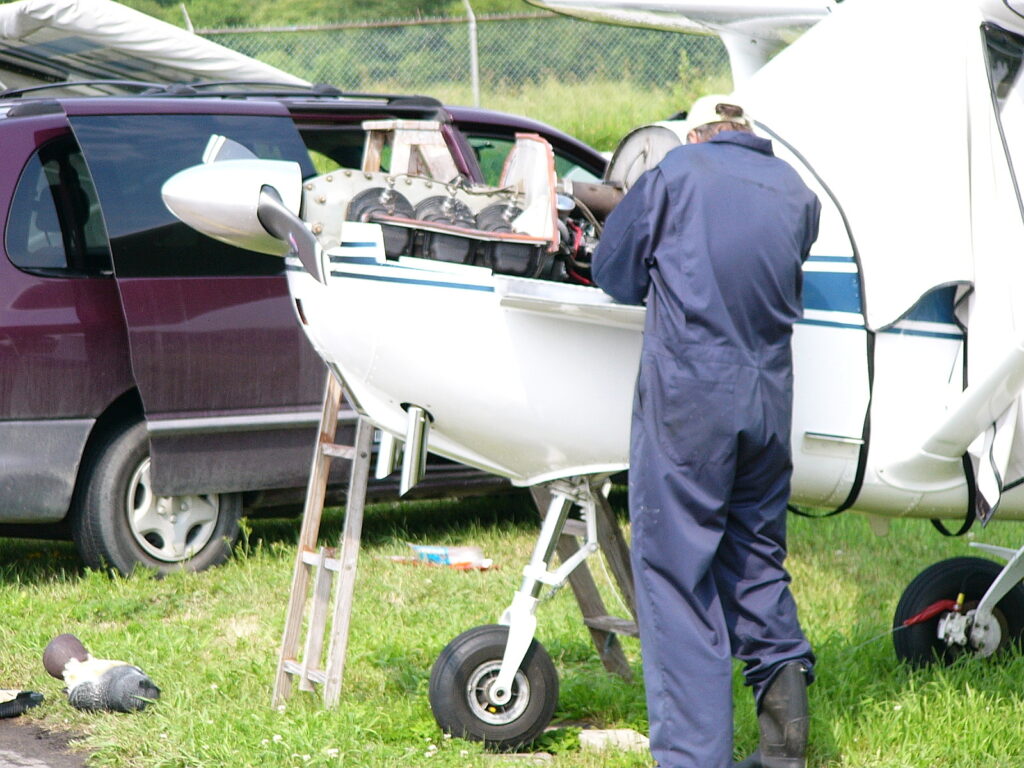 Mechaniker führt Wartungsarbeiten am geöffneten Kolbenmotor einer Cessna 172 durch