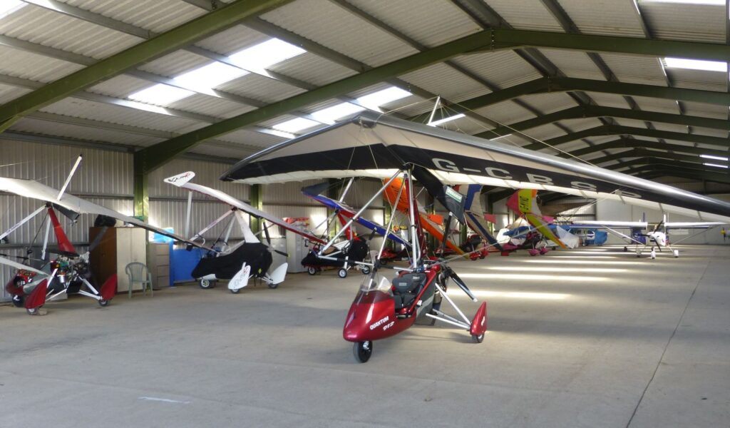 Mehrere Ultraleichtflugzeuge stehen dicht nebeneinander in einem Hangar
