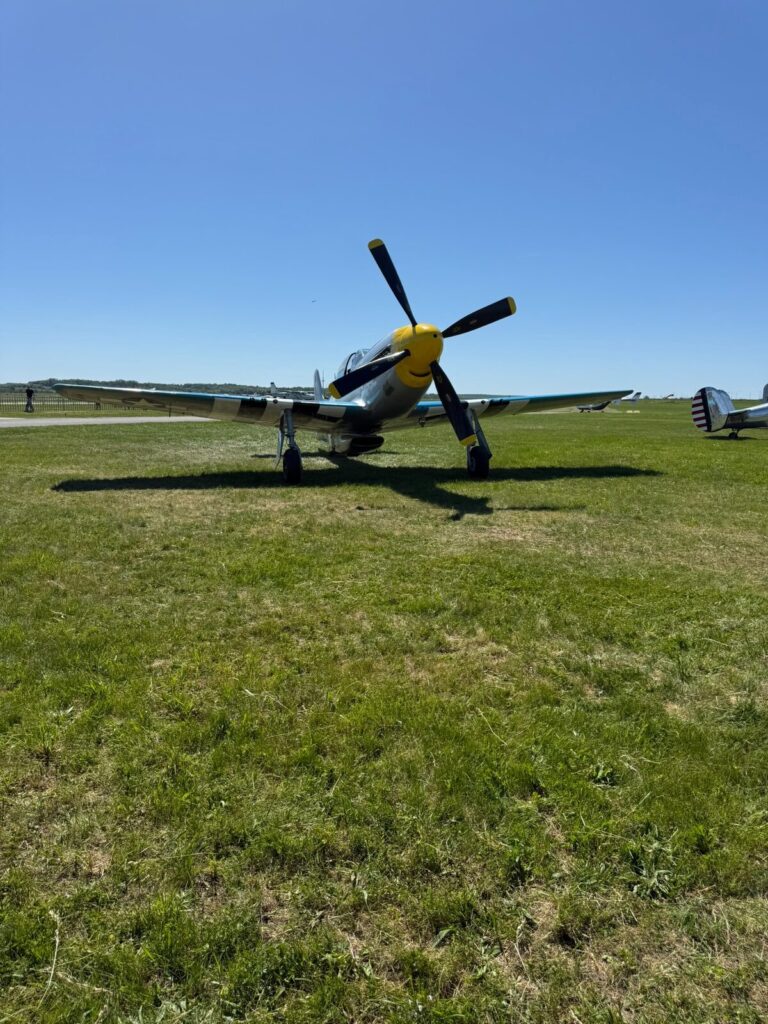 Historisches Flugzeug mit vierblättrigem Propeller auf einem Flugplatz.